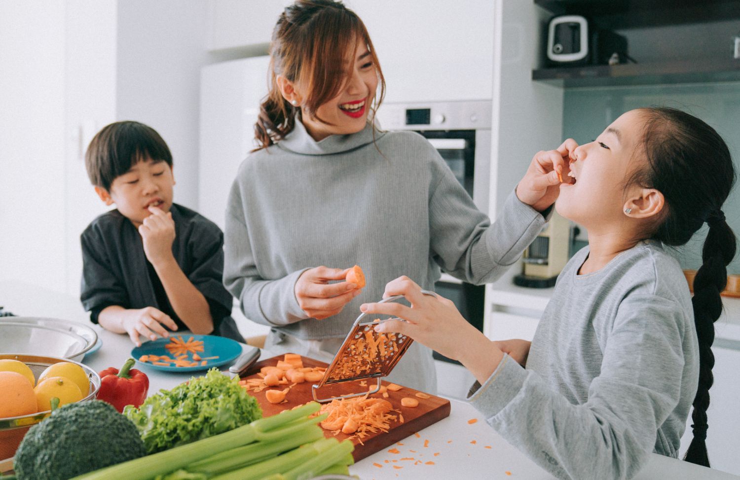 A family laughs while making a meal in the kitchen